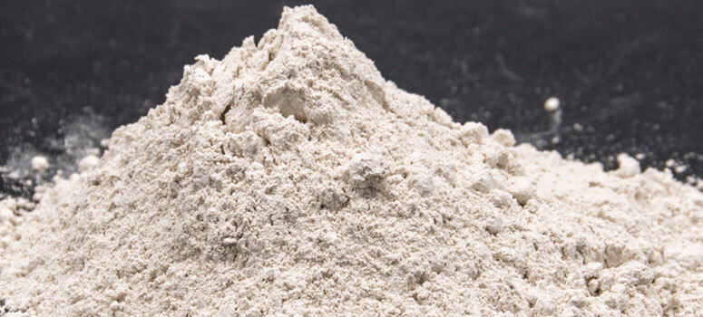 Pile of fine magnesite powder in light beige color, used for refractory, chemical and industrial applications.